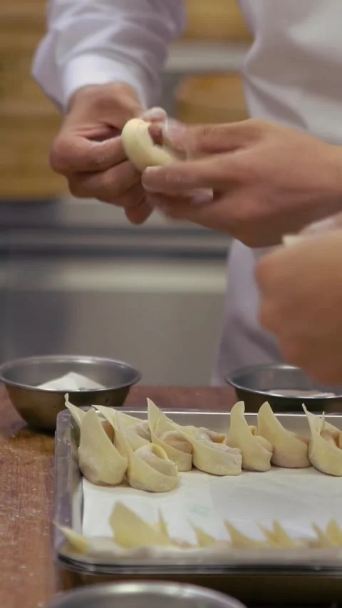 Vertical Taiwanese chefs in kitchen deftly crafting fresh dumplings by hand. Stock Footage 310853595