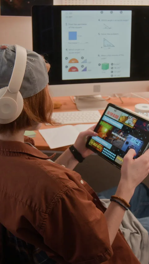 Vertical of Teenager Playing Mobile Game on Tablet and Ignoring Online Lesson Stock Footage 340772753