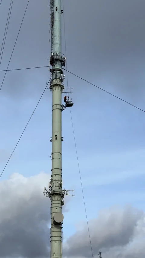 Vertical. Telecommunications tower climber going down in an open suspended cage. Stock-Footage 329126480