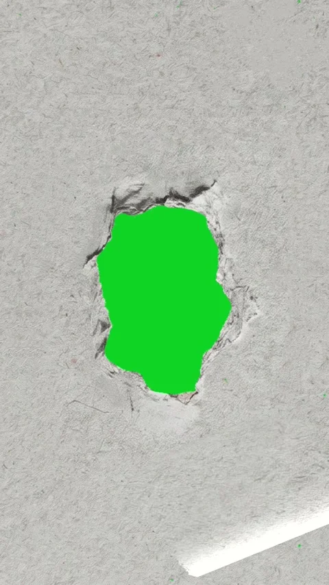 Vertical textured grey paper small jagged hole revealing animated on green Stock Footage 335216899