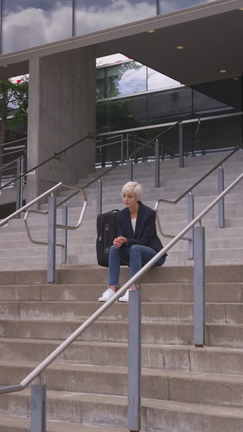 Vertical of Thoughtful Woman with Short Pixie Cut Sitting on Building Steps Stock Footage 208778528