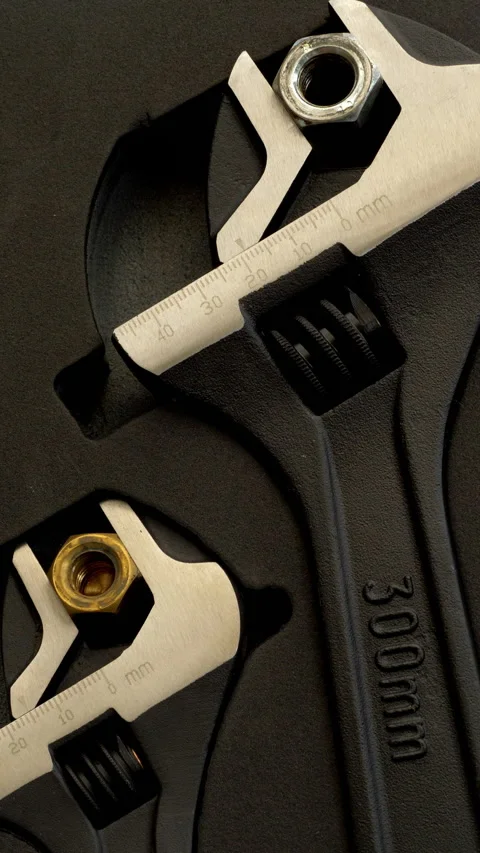 Vertical - Three different sized adjustable wrenches, each holding a steel nut. Vídeos de archivo 280113257