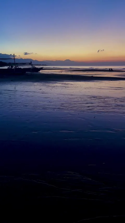 Vertical tilt up shot of beach dawn with boat silhouette in Bali Vidéo 343796782