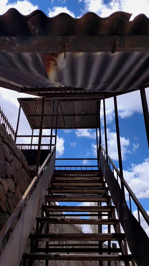 Vertical tilt shot of a rustic metal staircase with a rusted corrugated roof Vídeos de archivo 333908511