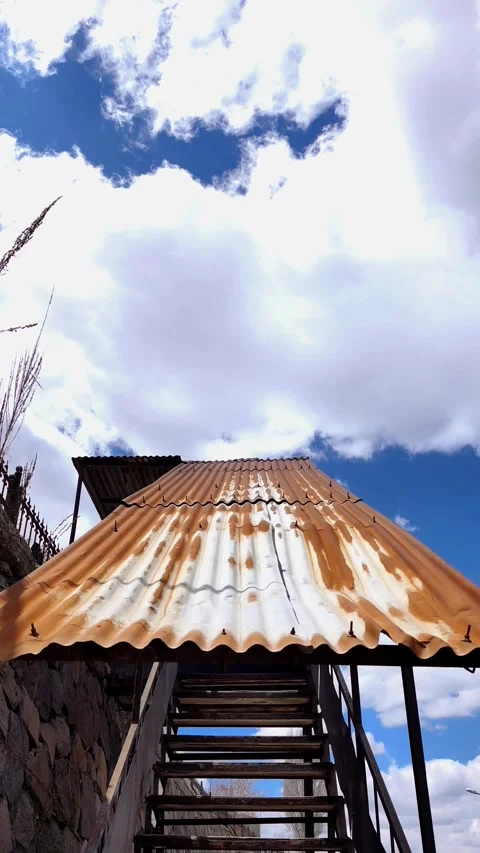 Vertical tilt shot of a rustic metal staircase with a rusted corrugated roof Stockbeeldmateriaal 333908515