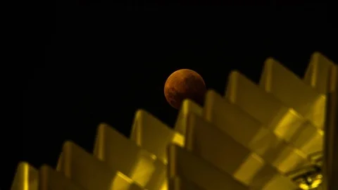 Vertical Time Lapse - Super Blue Blood Moon Rising Behind Blurred Spiked Roof Stock Footage 97758896