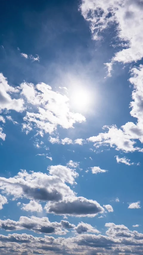 Vertical Time-Lapse of White Clouds Moving Across Sun Lit Blue Sky 動画素材 334137375