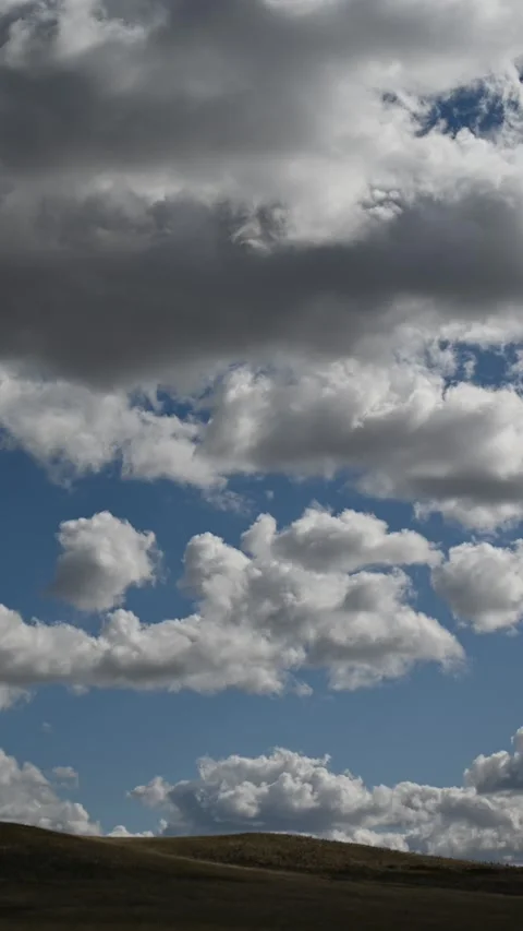 Vertical time lapse of white summer clouds moving above a barren prairie setting Stock Footage 300817600