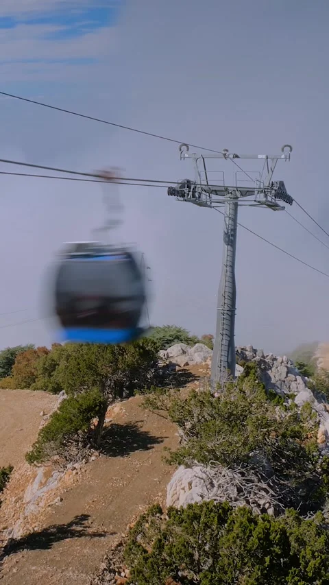 Vertical, timelapse: cable car cabins moving fast above mountain slopes, clouds Stock Footage 339029954