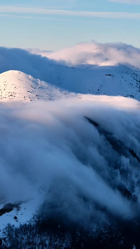 Vertical timelapse of clouds flowing like waterfall over snowy winter mountain Stock Footage 321751739