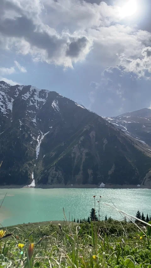 Vertical timelapse of clouds moving above a mountain lake with snow covered peak Stock Footage 342140074