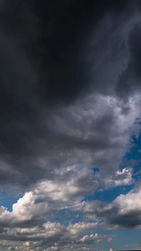 Vertical timelapse of dark clouds moving across an open blue sky, creating a... Stock Footage 341773842