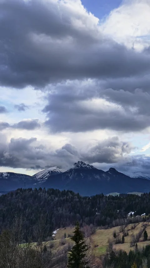 Vertical timelapse of dramatic storm clouds moving over snowy mountain peaks Stock Footage 336395470