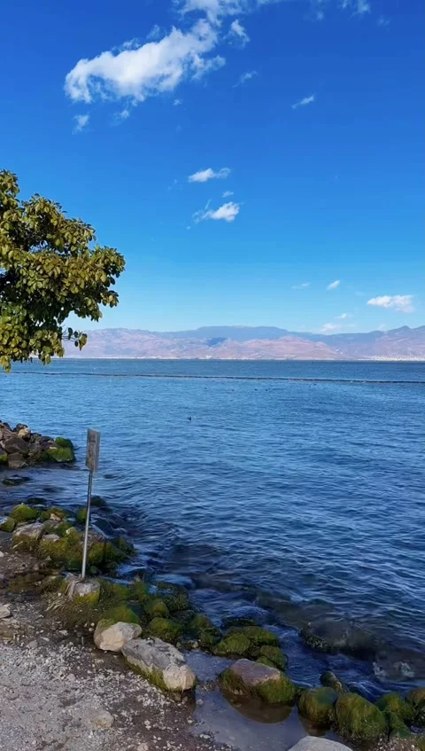 Vertical Timelapse of Fast Moving White Clouds over Blue Lake and Mountains Stock Footage 326078950