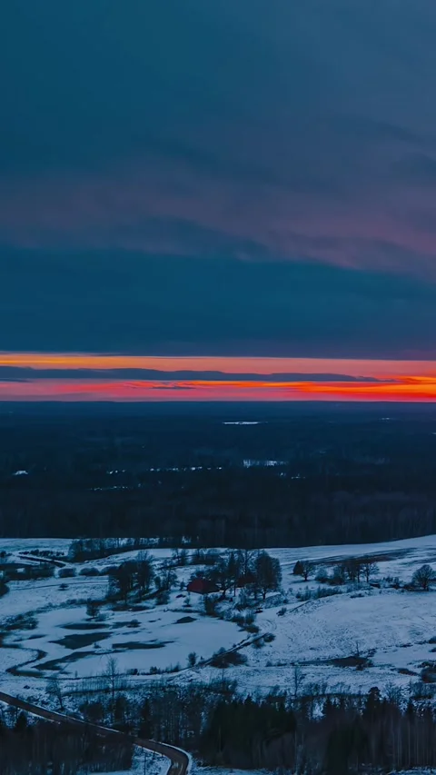 Vertical Timelapse Flying Forward Above Snowy Countryside at Fiery Sunset in Stock Footage 341677737
