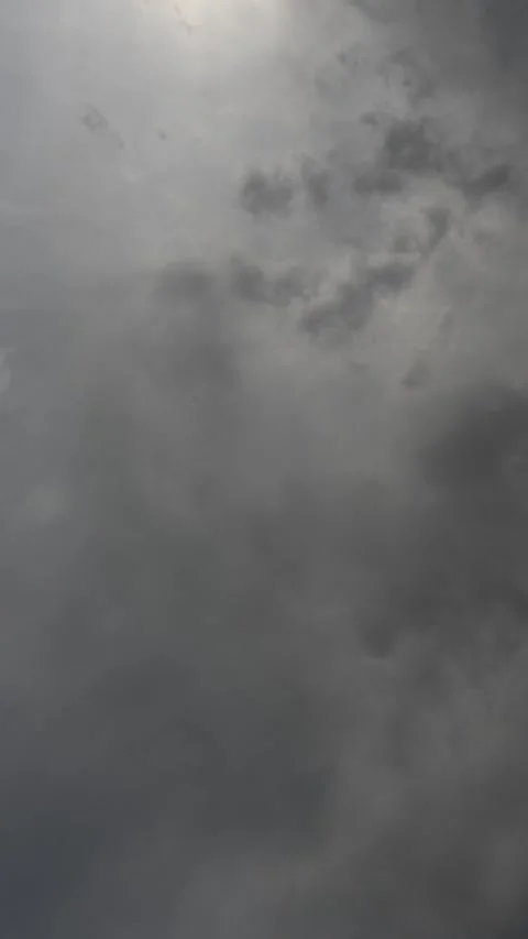 Vertical timelapse of gray storm clouds drifting across the sky with the sun at Stock Footage 311285384
