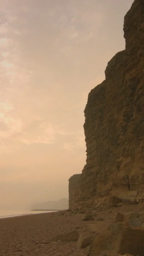 Vertical - Timelapse - sun sets next to large towering cliffs by the sea Stock Footage 283280508