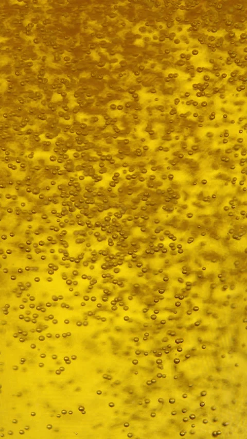 VERTICAL: Tiny co2 bubbles float around golden beer getting poured into a glass. Stock Footage 281093988