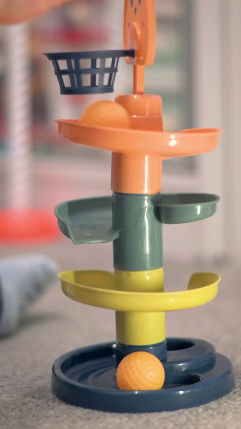 Vertical Toddler Drops Ball Through Basket In Spiral Ramp Tower Toy Stock Footage 330969536