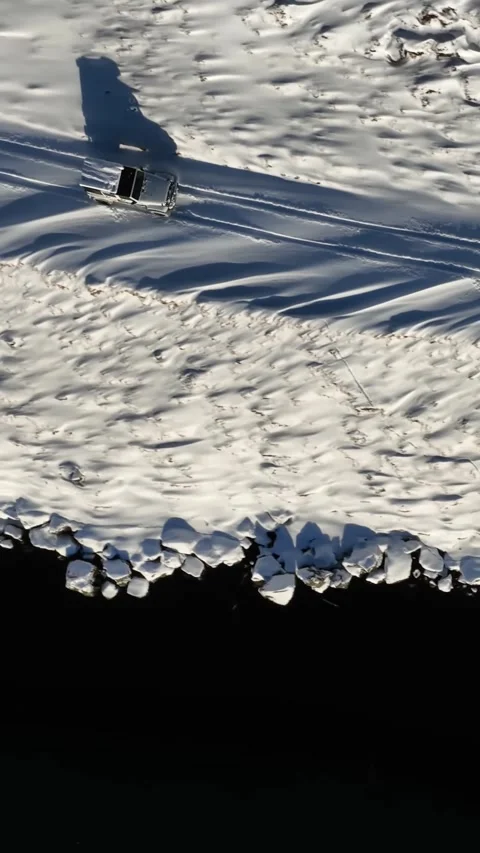 Vertical top down aerial view of a white off road vehicle driving beside dark 動画素材 334133762