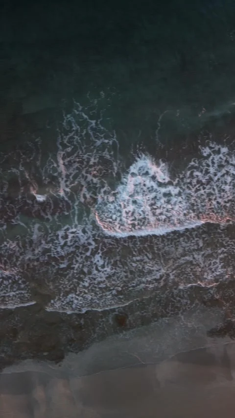 Vertical top down aerial view of turquoise sea waves and white foam on shore in Stock Footage 337405057