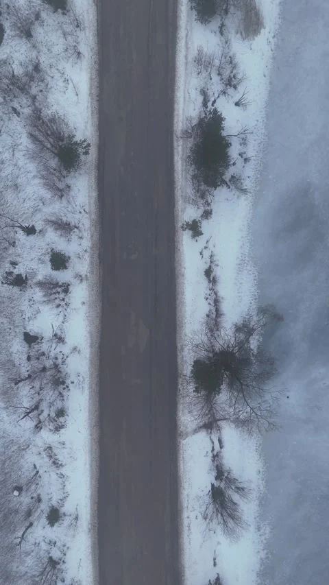 Vertical Top Down Drone Flight Over Snowy Road and Frozen Lake in Winter Stock Footage 340533057