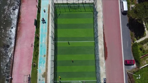 Vertical top-down drone footage of a soccer game on a green astroturf pitch dire Stock Footage 320125306