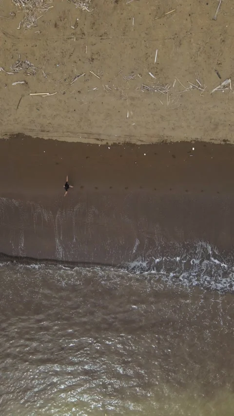 Vertical Top Down Drone Shot of Young Man Running on Wavy Beach Stock Footage 326332270
