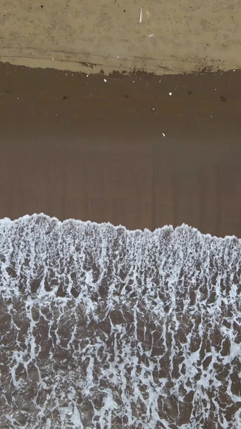 Vertical Top Down Drone Shot of Ocean Waves on Sandy Beach at Sunset Stock Footage 326332530