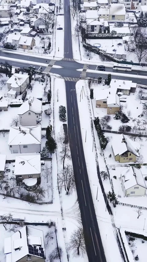 Vertical top-down drone view of a snowy suburban crossroad with zebra 動画素材 327917473