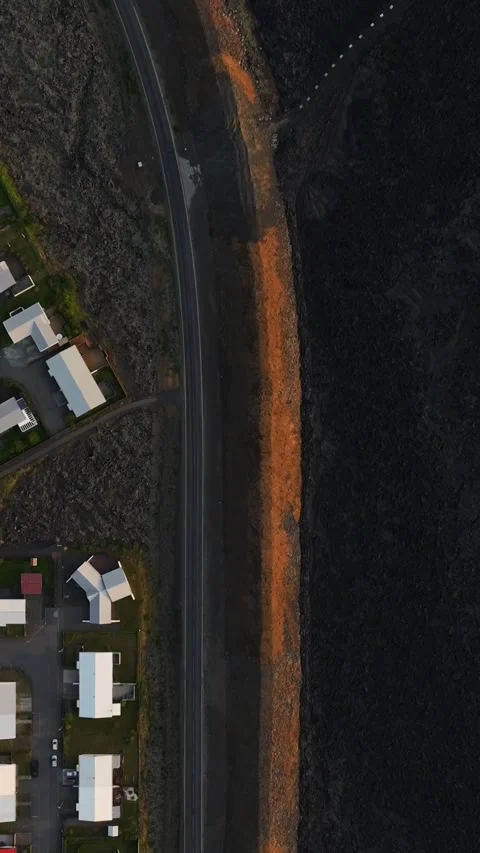 Vertical top-down drone view in Grindavik, Iceland, showing homes and a curved Vídeo Stock 345994664