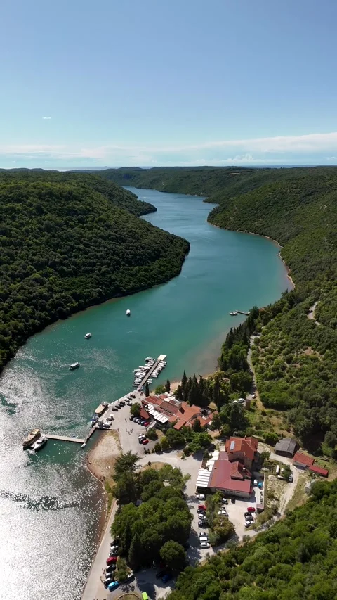 Vertical top-down view of a narrow emerald cove surrounded by green hills Stock Footage 322045358