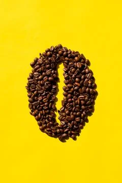Vertical top view of coffee beans in bean shape with yellow background. Stock Photos