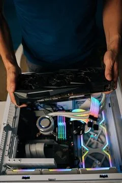 Vertical top view of computer technician installing high-end graphic card into Stock Photos