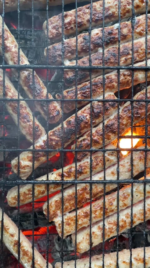 Vertical top view, flat lay sausages sizzling on grill Видео 308280566