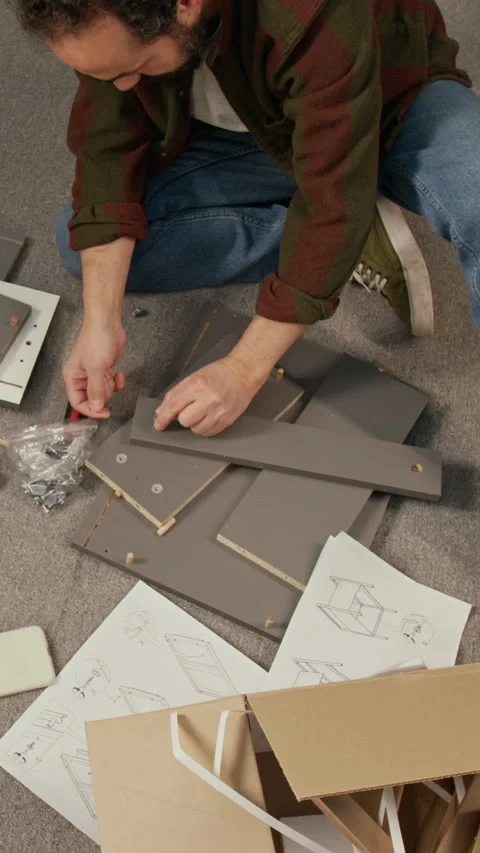 Vertical Top View of Man Assembling Flatpack Drawer to Instructions Stock Footage 330534874