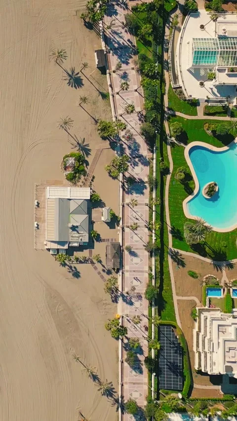 Vertical top‑down drone view of pedestrians walking along Puerto Banús beach Video stock 328153011