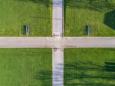 Vertical topview of crossing paths crossway surrounded by green gras Stock Photos