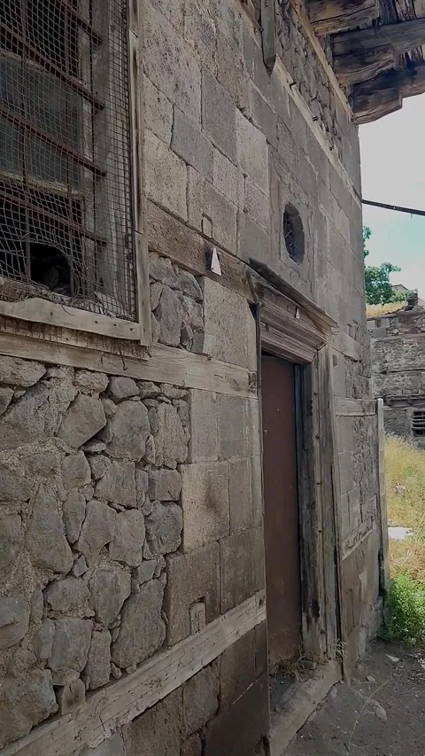 Vertical tracking shot along the facade of a dilapidated traditional stone a 動画素材 328402305