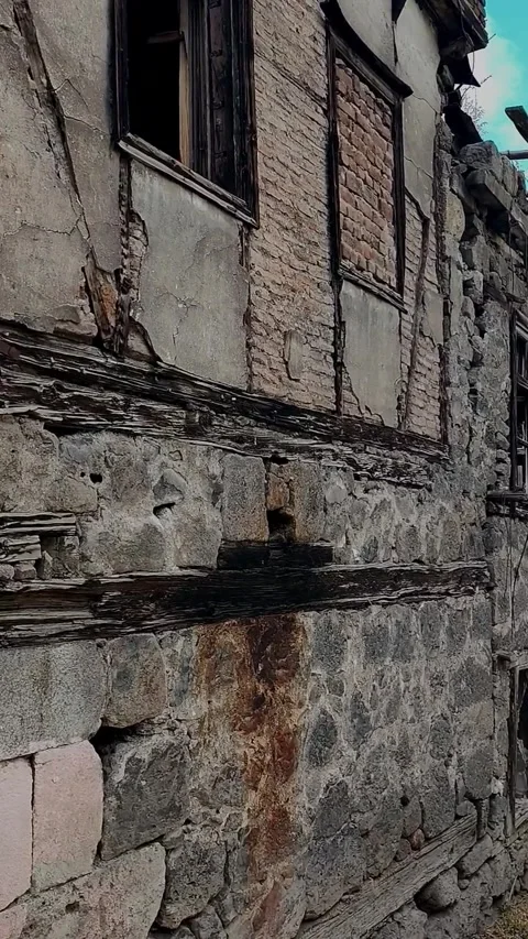 Vertical tracking shot along the ruined facade of an abandoned stone and bri 動画素材 328402355