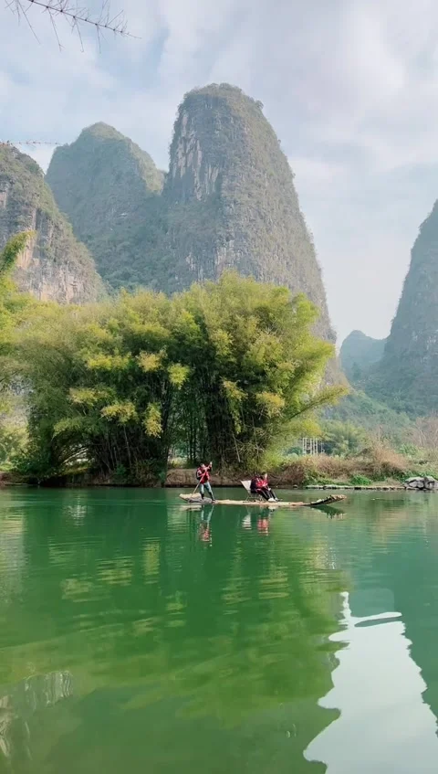 Vertical Tracking Shot of a Bamboo Raft Amidst Guilin Karst Mountains Stock Footage 328440400