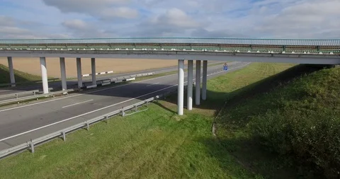 Vertical tracking shot of bridge over two-lane highway with cars moving  Stock Footage 101264299