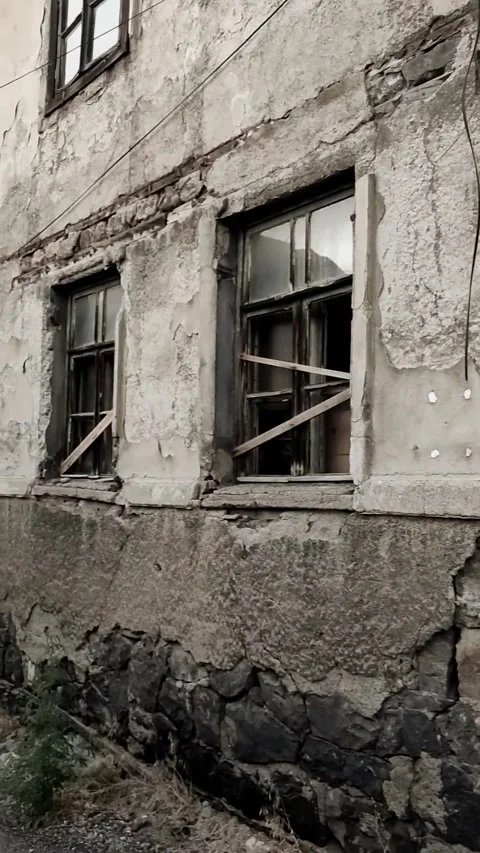 Vertical tracking shot of a dilapidated building facade in a slum area. Crum Stock-Footage 328402560