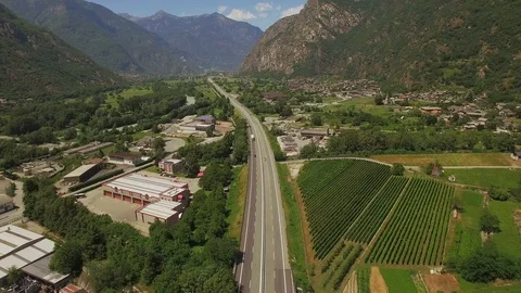 Vertical tracking video shot drone zooming out green mountainous valley highway  Stock Footage 96238364