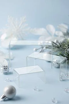 Vertical transparent acrylic podium set with silver ornaments on blue winte.. Fotos de archivo