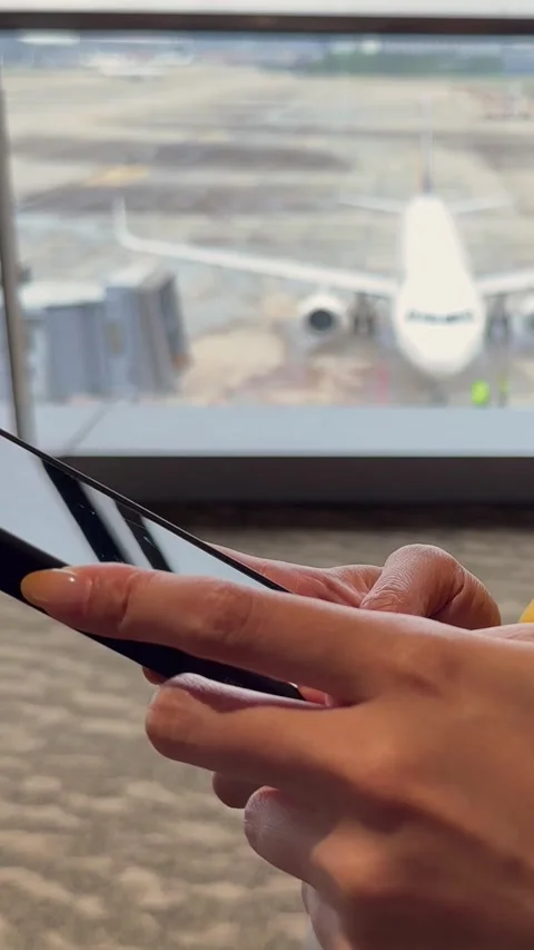 Vertical traveler using a smartphone with an airplane in view Stock Footage 313298886