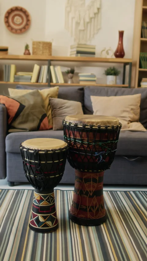 Vertical of Two African Drums of Different Sizes on Striped Rug in Living Room Stock Footage 319895196