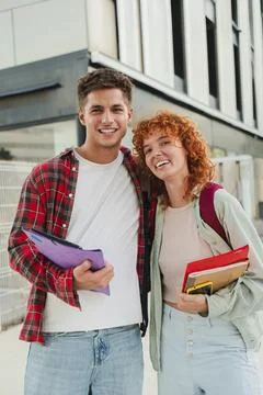 Vertical. Two cheerful classmates posing together outdoors, smiling warmly at Stock Photos