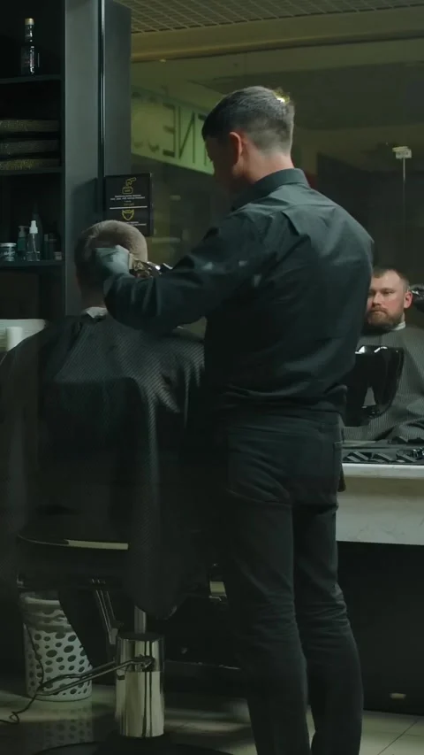 Vertical of Two clients and two hairdressers haircut in a dark barbershop room. Stock Footage 276877566
