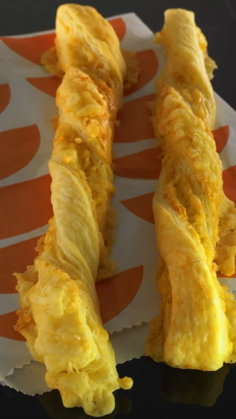 Vertical - Two freshly baked cheese straws on a takeaway packet. Stock Footage 288336583